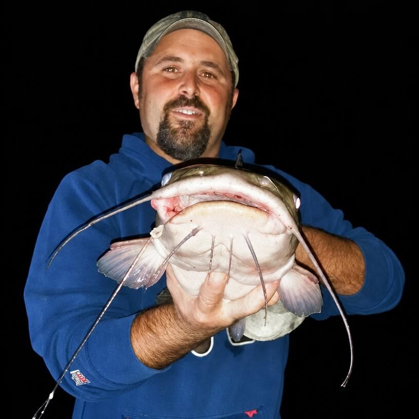 Ron Stevenson holding a catfish at night